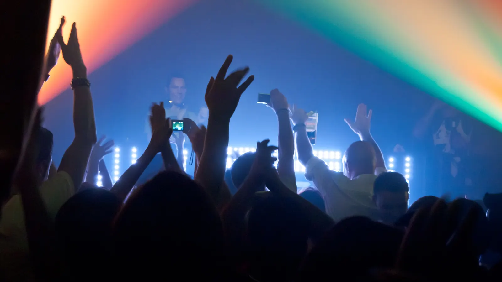 Crowd and coloured stage lights during an electronic music party in a Bangkok club