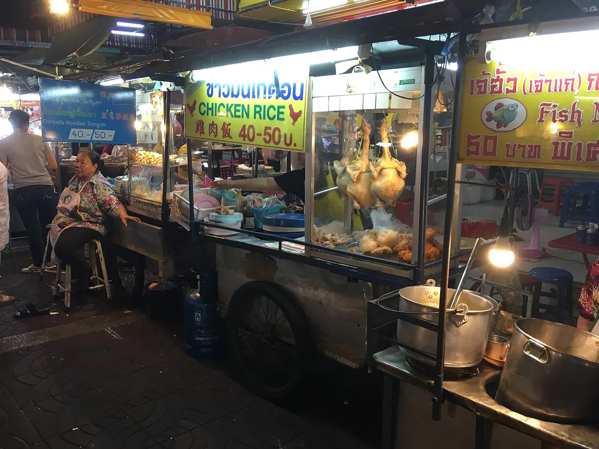 Food stalls lit up on a Chinatown street at night